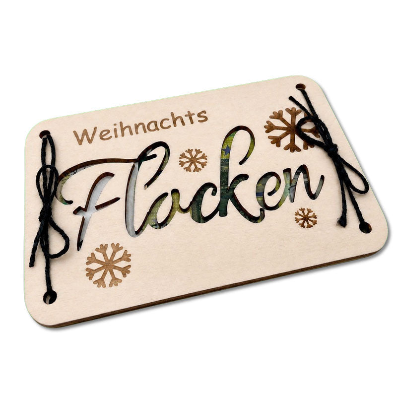 Schrägansicht des weihnachtlichen Geldgeschenks aus Holz mit ausgeschnittenem Schriftzug „Flocken“